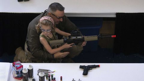Un hombre muestra a una ni�a c�mo sostener un arma durante la convenci�n anual de la Asociaci�n Nacional del Rifle del 2013, en Houston