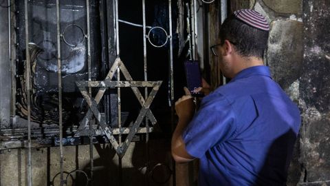 Un judío israelí observa los daños en una sinagoga incendiada en la ciudad mixta de Lod