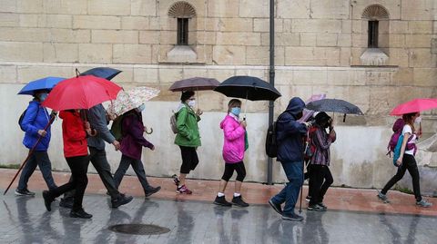 Un grupo de peregrinos se protegen de la lluvia con paraguas