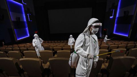 Trabajadores desinfectan un teatro en Bangkok antes de su reapertura