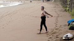 Un surfista realiza estiramientos antes de entrar al agua en la Playa de San Lorenzo de Gijn
