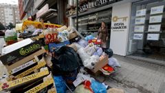 La propietaria de la inmobiliaria junto al mont�n de basura que oculta su local.