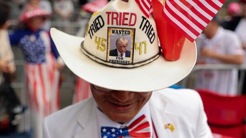 Un hombre lleva un sombrero con la foto policial de Trump, mientras la gente espera en fila para ser de los primeros en ingresar a la ruta del desfile para conmemorar el 250 aniversario del Ej�rcito de los Estados Unidos en Washington
