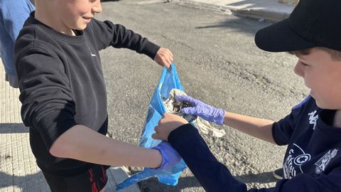 Dos alumnos de primaria del CPR de Fisterra retiran 'basuraleza' en una de las actividades del centro.