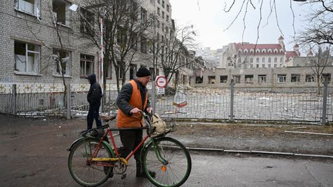 Personas caminando cerca de una escuela destruida por los ataques rusos en Ucrania