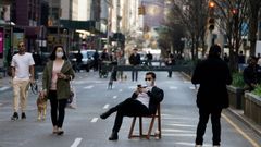 Un hombre permanece sentado en Park Avenue, cortada a causa del coronavirus.