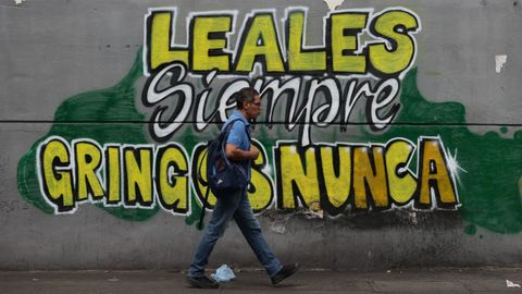Un hombre camina ante un mural en Caracas