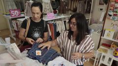 La due�a de la tienda 5 Lobi�os, de Foz, mostrando prendas de uniformes a una clienta