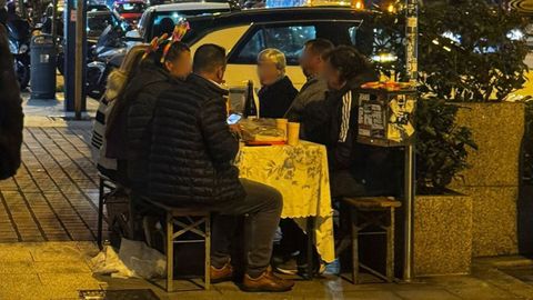 Varios turistas en las calles de Vigo instalando una mesa con mantel en plena calle