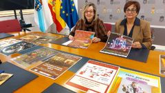 Marina Doutn y Gloria Prada con carteles de las diferentes actividades del programa