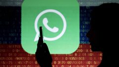 Una mujer usa el m�vil frente al logo de WhatsApp