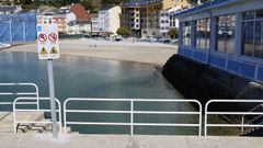 La se�al que proh�be el ba�o y la pesca en la zona del muelle viejo de Celeiro, con la playa al fondo