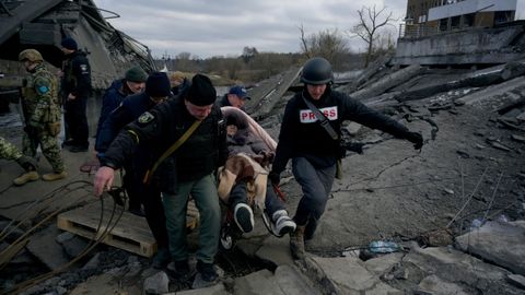 Varios voluntarios y un periodista ayudan a una mujer en Romanivka, cerca de Odesa 