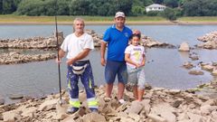 Pepe, vecino de Nar&oacute;n (izquierda) y Juan Carlos, de Mugardos, con su nieta, Lara, la &uacute;ltima jornada de pesca fluvial de la temporada, con las ruinas de varias viviendas del pantano de As Forcadas a la vista