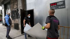 Dos operarios y un vigilante sellando un edificio okupa de Vigo