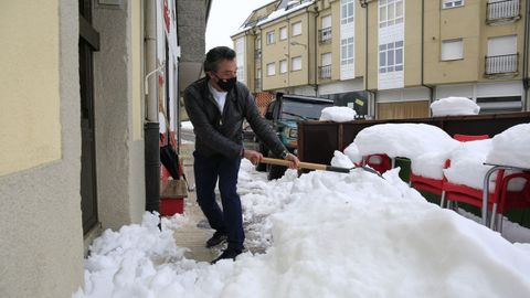 El propietario de la Carnicera Bolao de O Cadavo retira la nieve decla entrada de su negocio en el que sigue din luz elctrica 