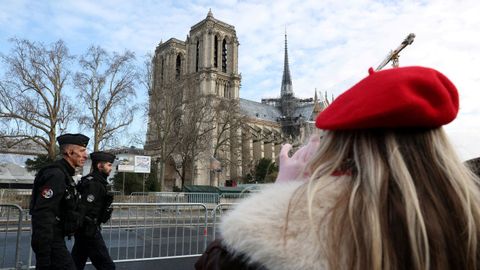 Una visitante toma una foto de Notre-Dame, fuertemente protegida por las fuerzas de seguridad