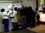 Un grupo de personas mira las listas de los seleccionados.