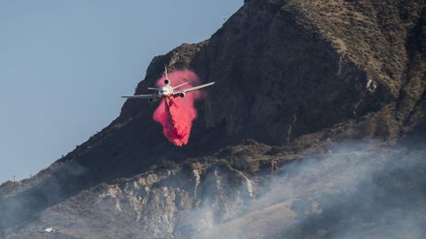 Un avi�n arroja retardantes del fuego sobre las colinas cerca de Ventura