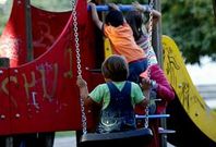 Ni�os jugando en los columpios de un parque infantil, en una fotograf�a de archivo