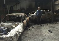 El director, junto a coches calcinados en el taller del instituto. 