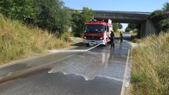 Bomberos del parque de Chantada limpiando un vertido de aceite en una carretera, en una imagen de archivo
