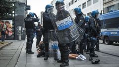 Agentes de la polic�a italiana, equipados con material antidisturbios, rodean a una persona que yace en el pavimento durante unos disturbios cerca de la Piazza del Duomo, en Mil�n (Italia) a mediados de octubre. .