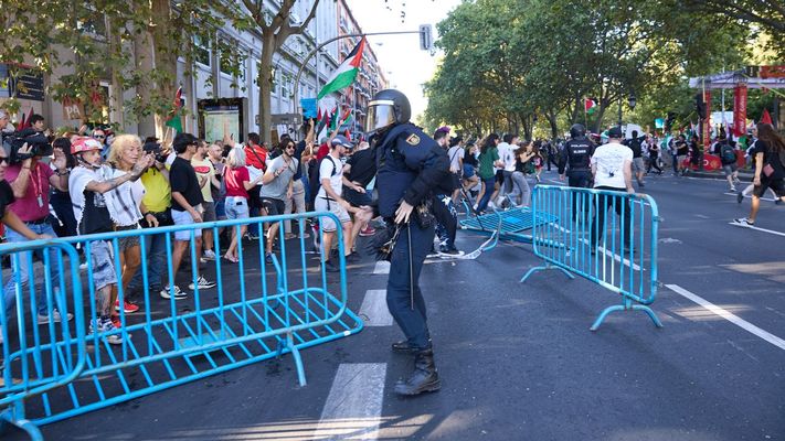 Un agente de Policía Nacional entre vallas tiradas tras cargas policiales a manifestantes en la etapa final de la Vuelta Ciclista a España, en Madrid.
