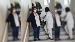 En la imagen, tres trabajadoras bajando una silla de ruedas por las escaleras tras haber ayudado a bajar a pie a su ocupante, una persona que sufre problemas de movilidad por un ictus 