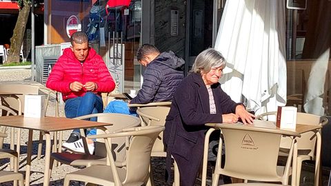 Varias personas sentadas y tomando caf� en una terraza de Oporto.