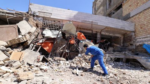 Un hombre retira escombros de un edificio residencial bombardeado en Karaj