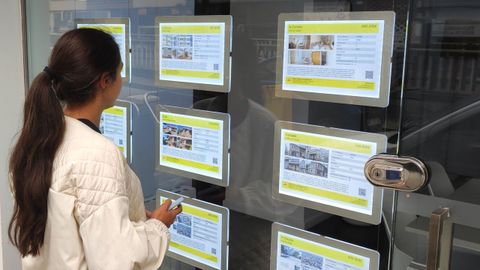 Una joven ante el escaparate de una inmobiliaria coruesa.