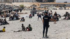 Un agente de polic�a patrulla en playa del Trampol�n mientras los migrantes esperan para entrar en un centro de acogida de migrantes de corta estancia (CETI). 