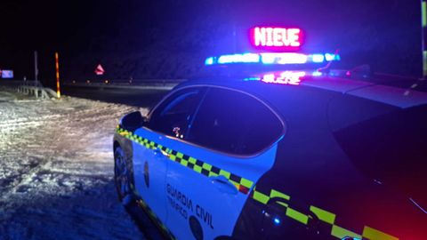 Imagen de un coche de la Guardia Civil durante una nevada del mes de diciembre del 2025 en una carretera de Ourense.