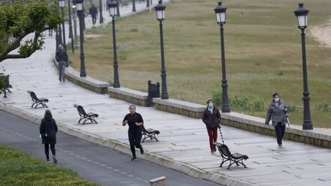 Deportistas y viandantes en el paseo de Coroso en Ribeira