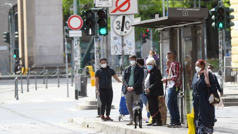 Personas con mascarillas esperan en una parada de autobs en Miln, Italia.