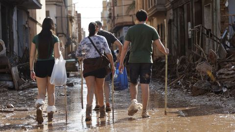 Varias personas caminan entre el lodo acumulado