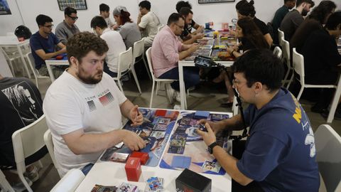 Varios jugadores disputan partidas en la tienda Mazinger de Vigo, uno de ellos mientras la graba. 
