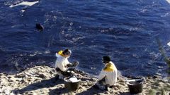 Dos voluntarios recogiendo fuel en la isla de Ons, en diciembre del 2002
