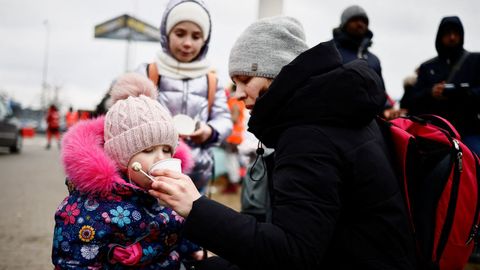Una madre da agua a su hija mientras huyen de la invasi�n rusa de Ucrania, en un campamento temporal en Przemysl, Polonia