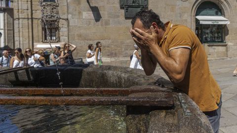 Un hombre se refresca en la fuente de Prater�as, en Santiago.