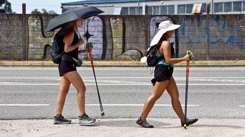 Peregrinas asi�ticas haciendo el Camino de Santiago, en San Miguel de Oia, con un paraguas para protegerse del calor en una imagen de archivo.