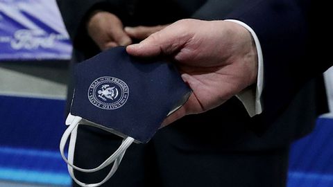 Trump sostiene una mascarilla con el distintivo de la Casa Blanca