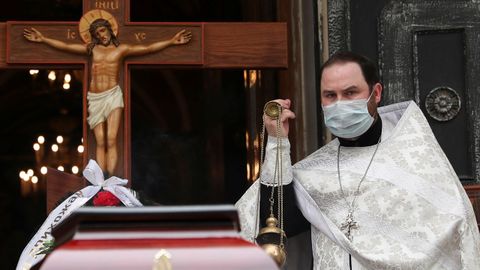 Un sacerdote con una mscara protectora celebra un servicio funerario junto al atad del dicono ortodoxo Andrei Molchanov,  quien muri despus de contraer la enfermedad por coronavirus en Mosc
