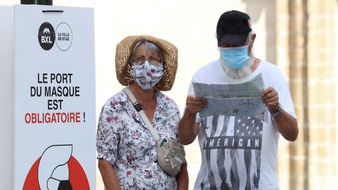 Personas usando mascarillas junto a un aviso que indica la obligatoriedad de las mismas en Bruselas, B�lgica.