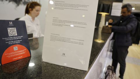 hotel.Cartel anunciando la implantacin de la tasa turstica en la recepcin de un hotel de A Corua este martes
