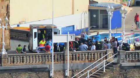 Polica y Bomberos tratan a la mujer que se ha cado en la escalera 1 de la playa de San Lorenzo, en Gijn