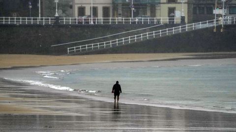 Un hombre camina este mircoles por la playa de San Lorenzo en Gijn