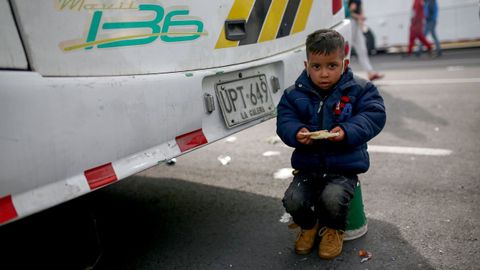 Un nio migrante venezolano come durante la parada del autobs que los lleva de regreso a su pas