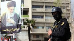 Un miembro de la seguridad iran� junto a un cartel de Al� Jamen�i.